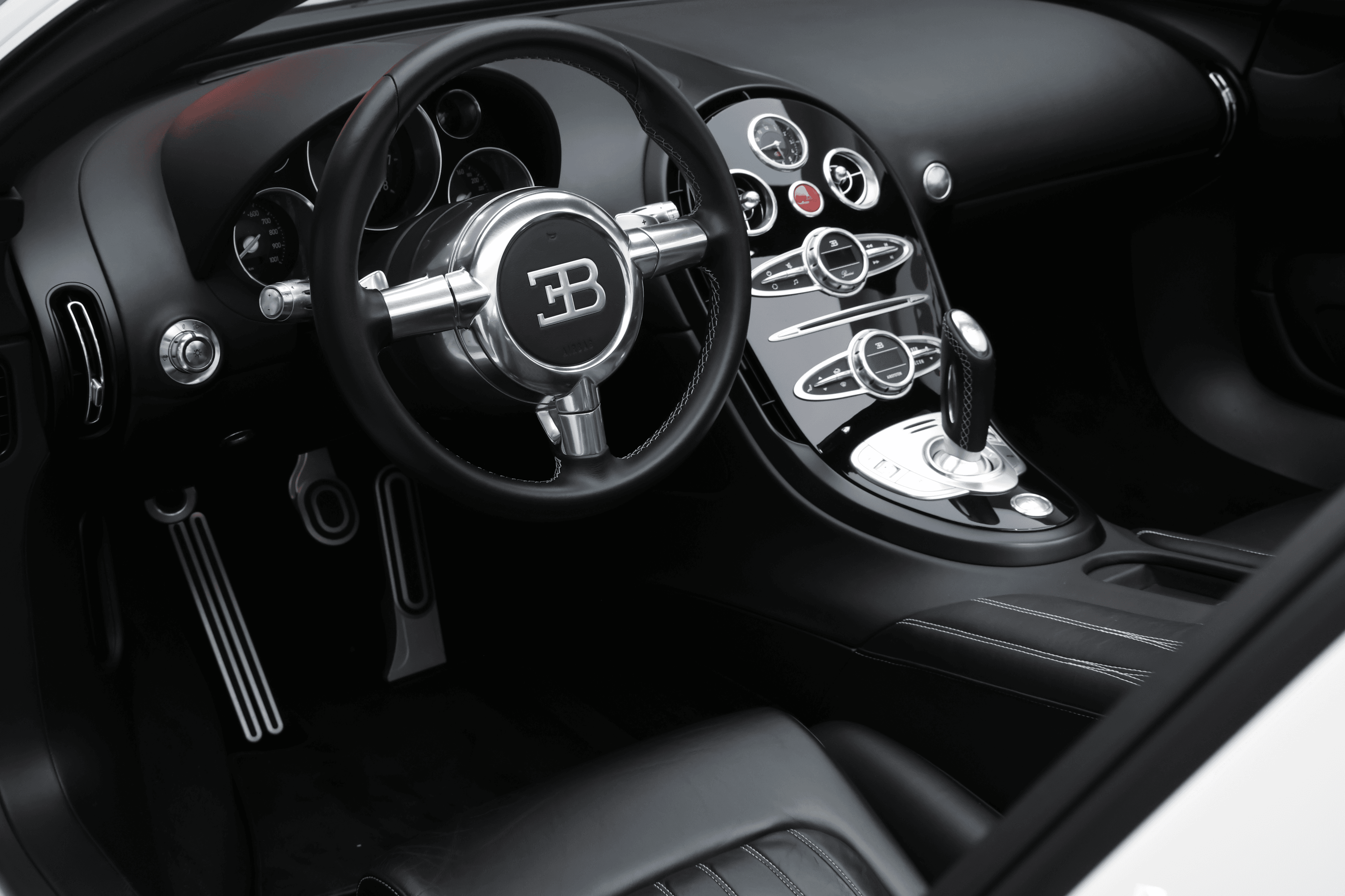 Installé derrière le volant, l'intérieur de la Bugatti Veyron s'ouvre sur une console centrale raffinée, où les commandes intuitives et les matériaux luxueux créent une ambiance de performance et de sophistication inégalée.