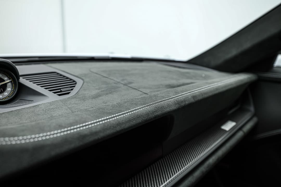 Cette image du tableau de bord en Alcantara de la Porsche 911 GT3 RS souligne le luxe et la sportivité, offrant une texture agréable au toucher tout en améliorant l'adhérence et le style, pour une expérience de conduite à la fois raffinée et dynamique.