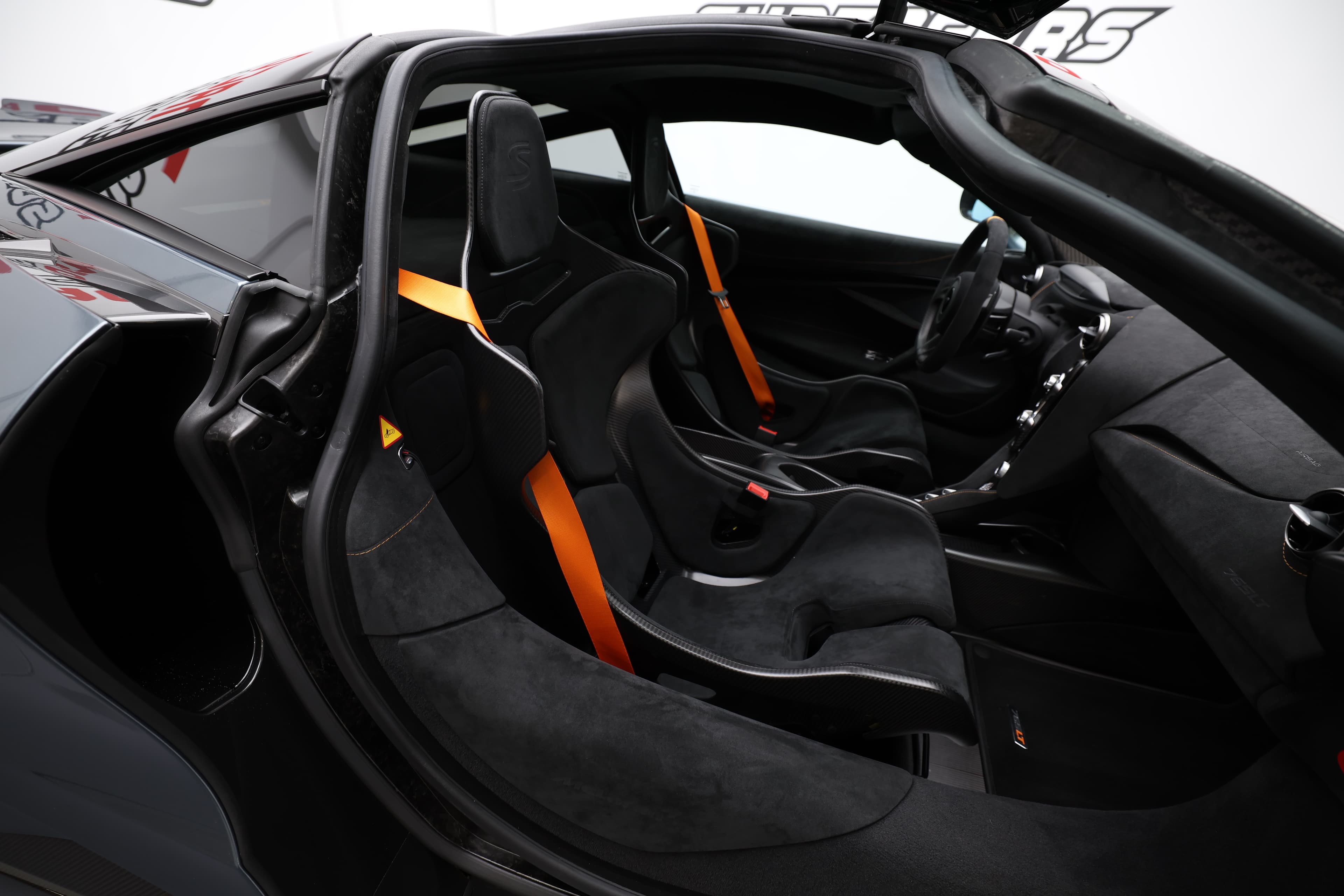 L'image met en avant l'intérieur côté passager de la McLaren, mettant en lumière le siège, qui allie confort et sportivité, ainsi que les matériaux luxueux et les finitions haut de gamme qui caractérisent cette supercar emblématique.