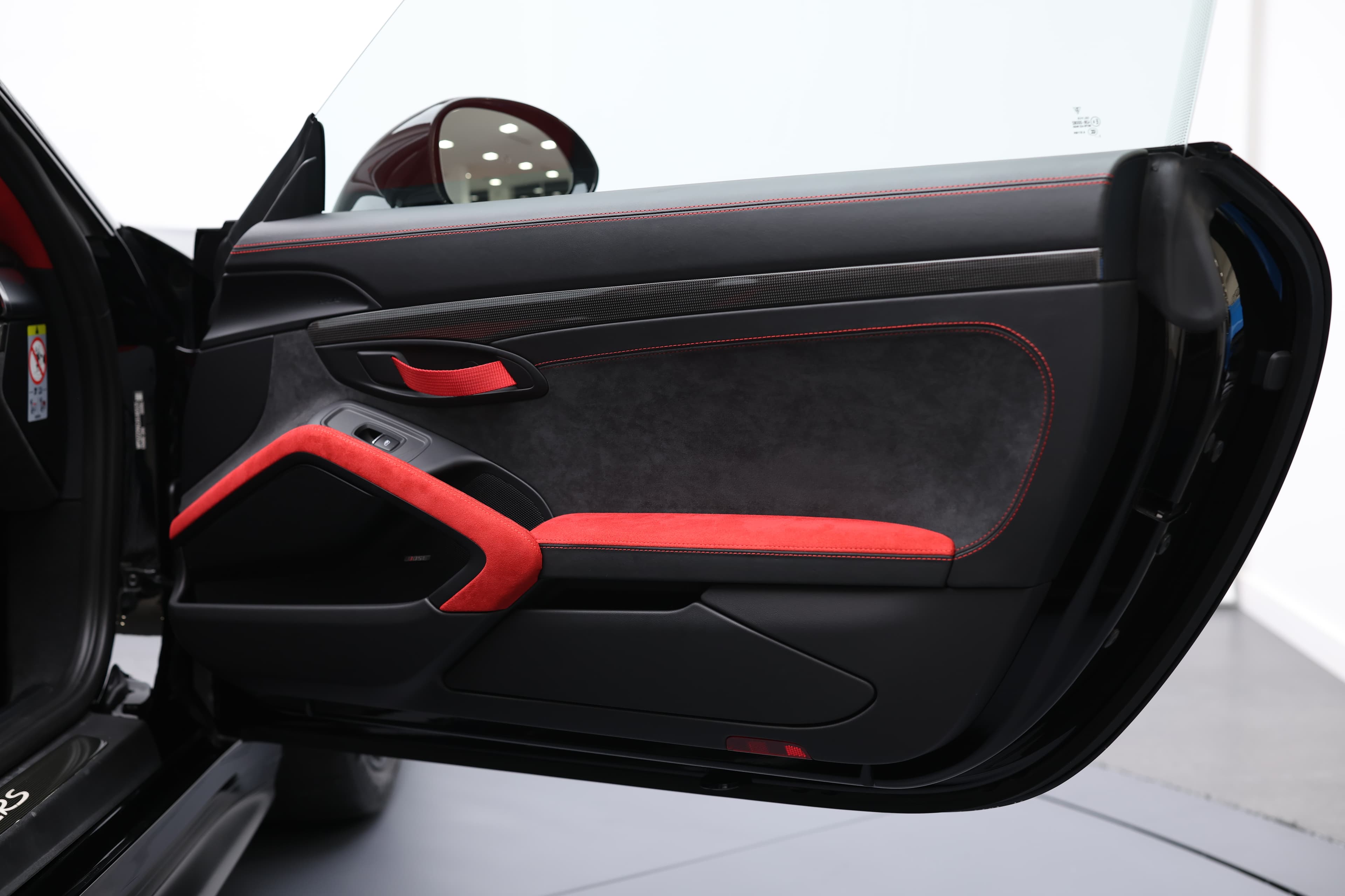 Photo de l'intérieur de la porte de la Porsche 911 GT2 RS, mettant en valeur les surpiqûres rouges qui ajoutent une touche de sportivité et d'élégance au design intérieur haut de gamme.