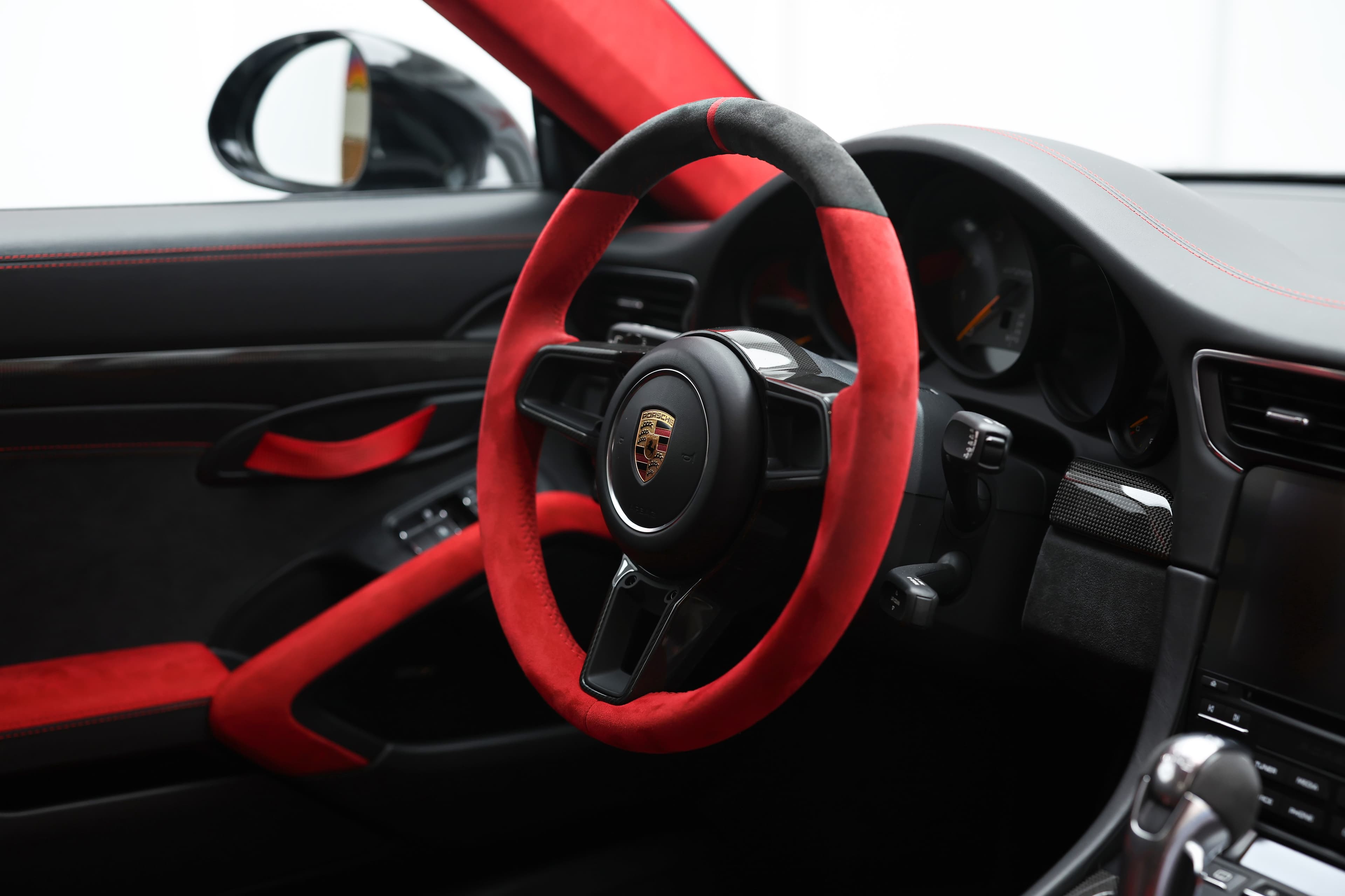 Photo du volant en Alcantara noir et rouge de la Porsche 911 GT2 RS, offrant une prise en main optimale et un style audacieux qui accentue l'aspect sportif de l'intérieur.