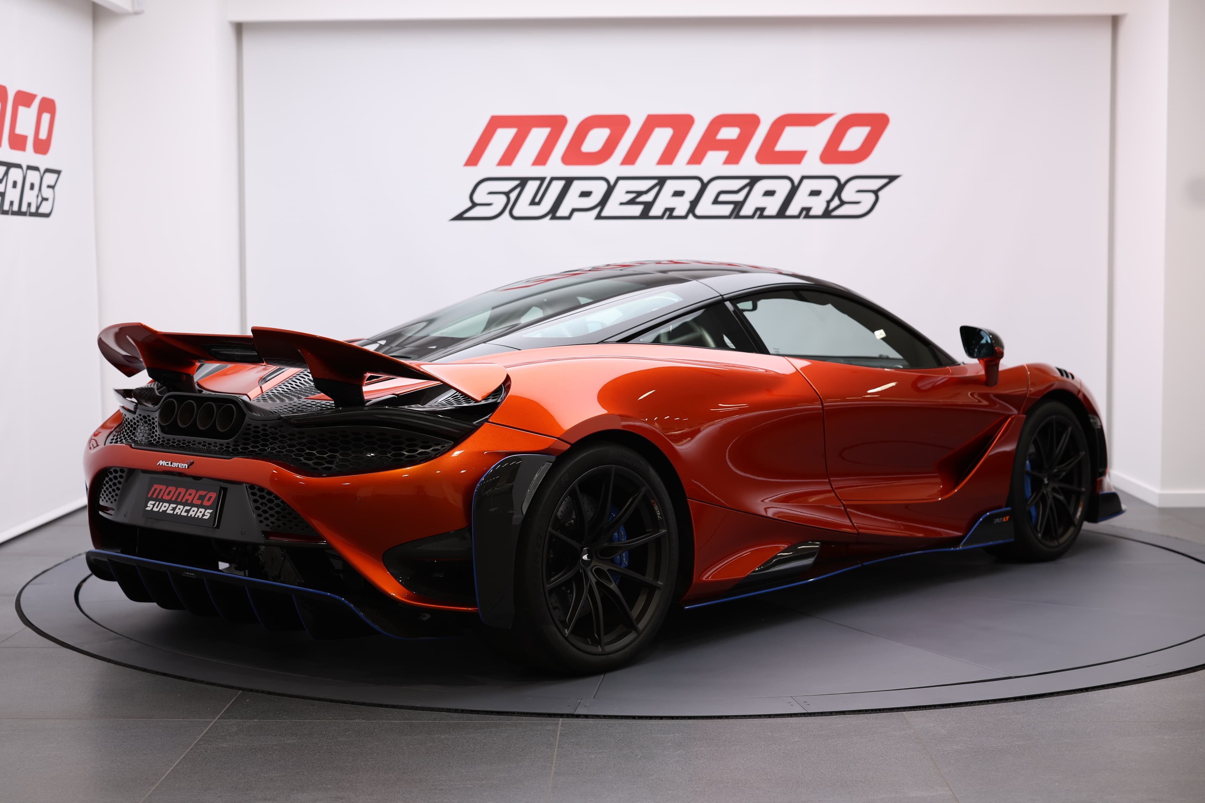 Vue latérale et arrière de la McLaren 765LT, mettant en avant son aileron arrière et son design sculpté, soulignant l'accent mis sur l'aérodynamisme et la performance.