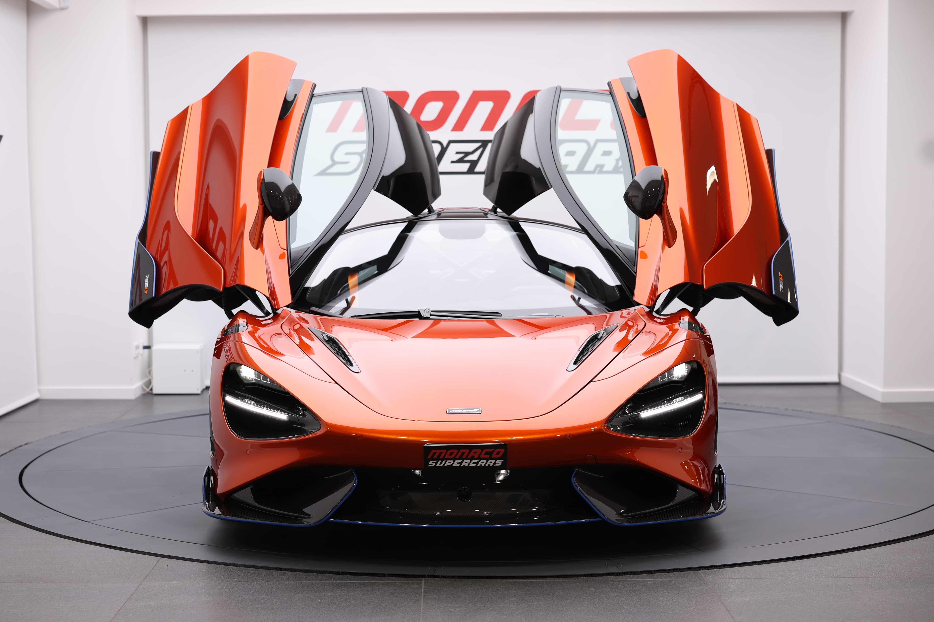 Vue frontale de la McLaren 765LT avec les portes en élytre ouvertes, mettant en avant son design unique et emblématique, accentuant l'aspect futuriste et distinctif de cette supercar.