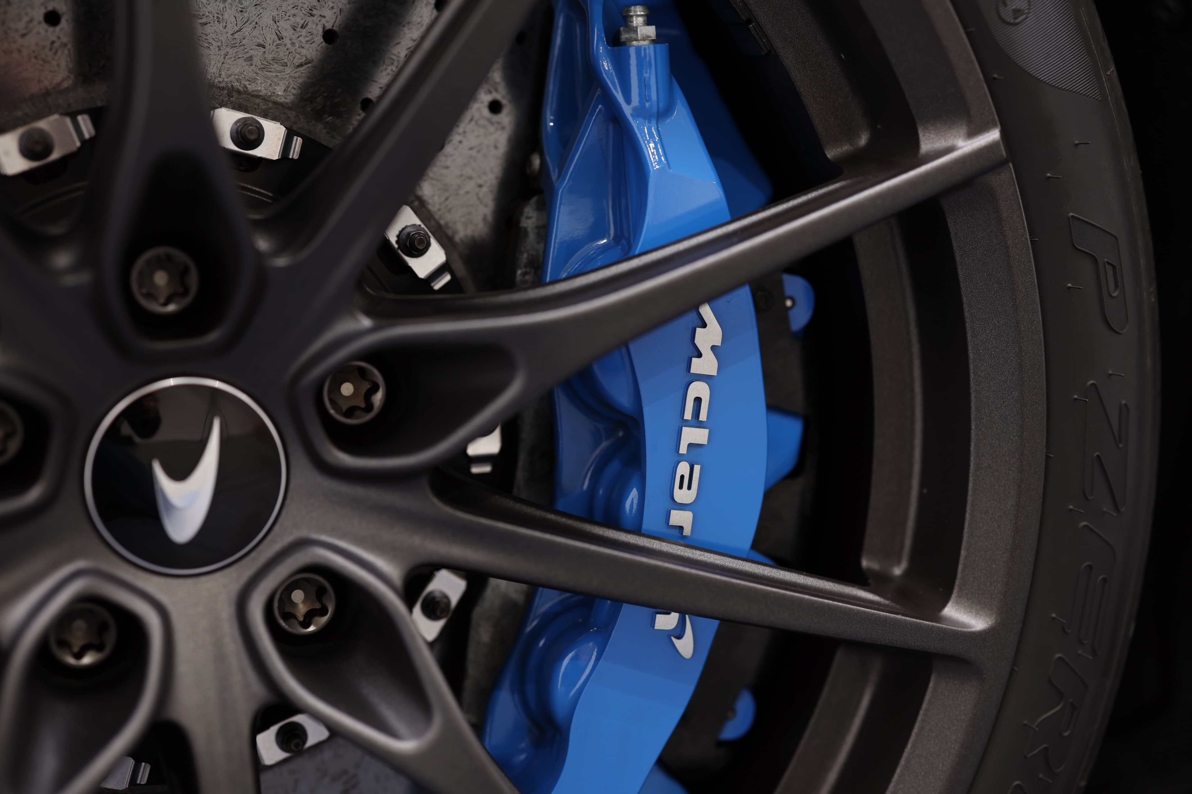 Gros plan sur la jante de la McLaren 765LT, mettant en avant les freins en carbone-céramique et le design sophistiqué de la jante, soulignant l'importance de la performance et de la technologie dans cette supercar.