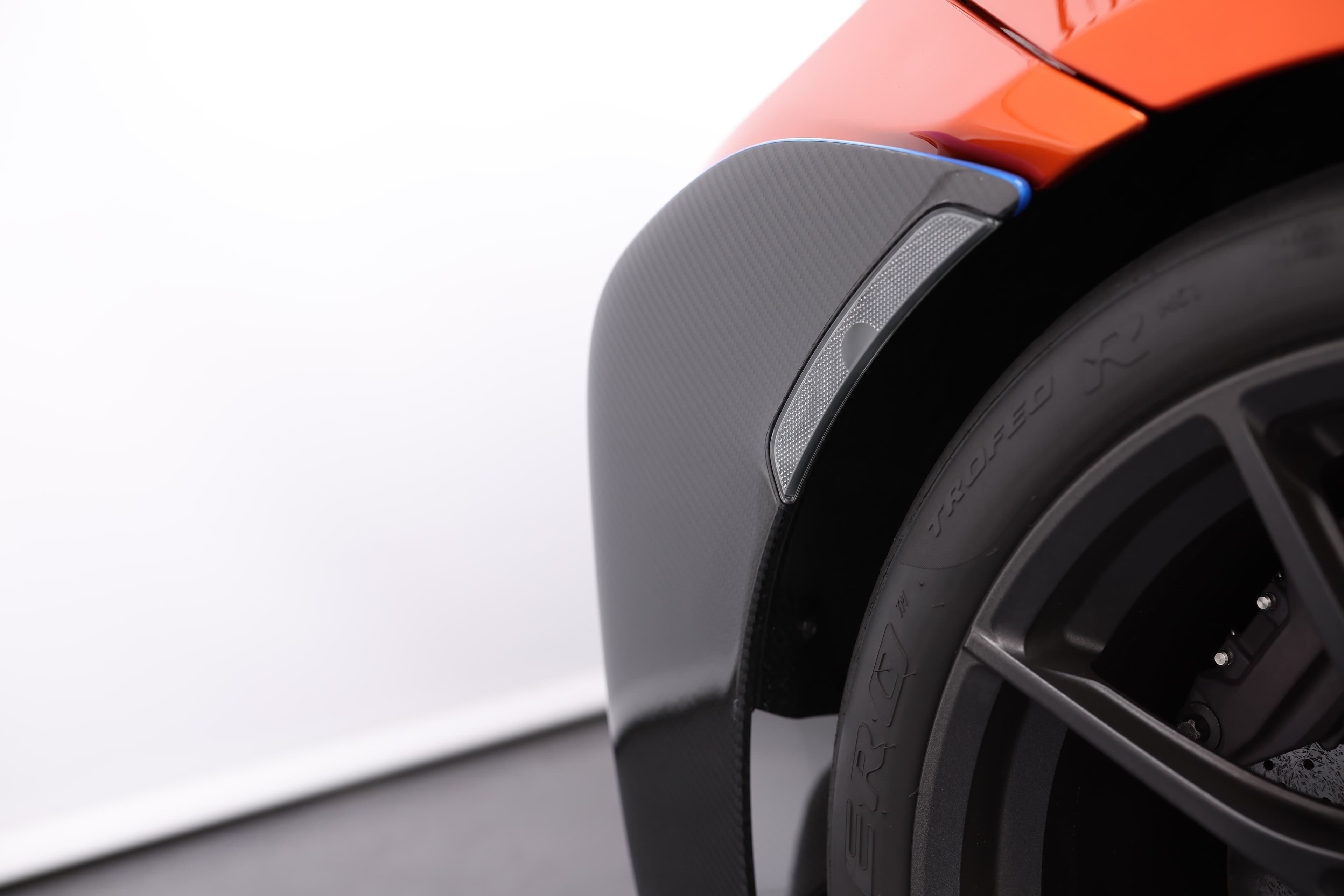 Gros plan sur le détail du passage de roue de la McLaren 765LT, mettant en avant les éléments en carbone et le design soigné, illustrant l'accent mis sur la performance et l'esthétique.