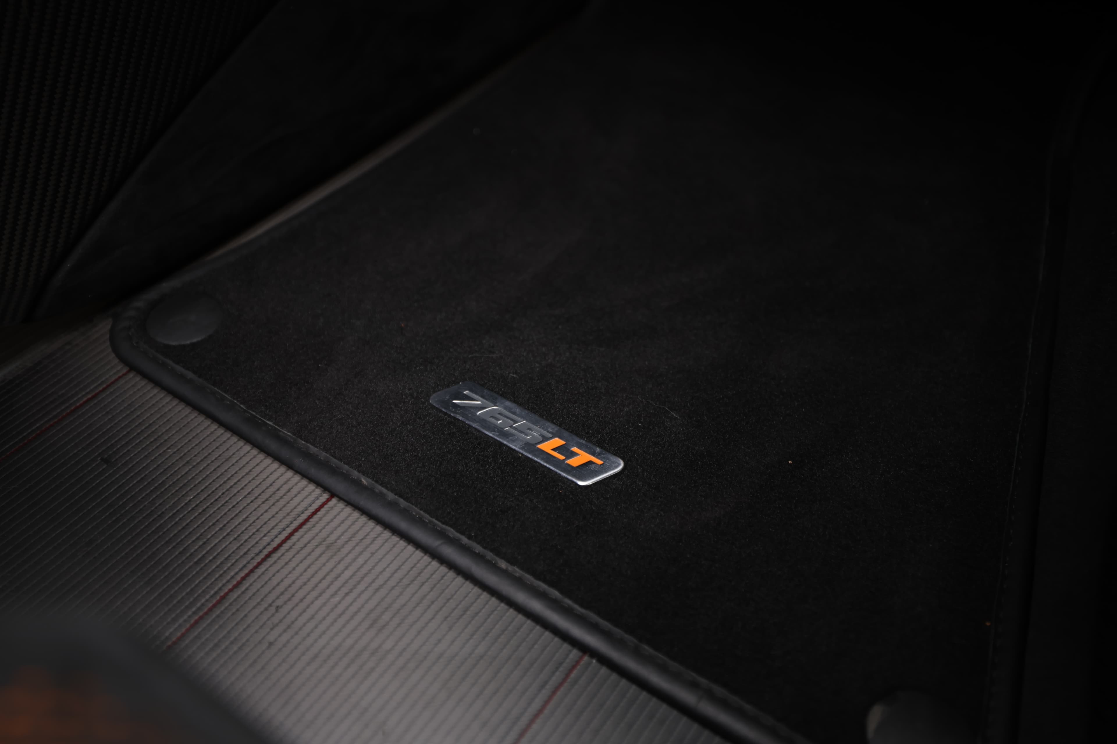 Gros plan sur le badge signature de la McLaren 765LT, mettant en avant la personnalisation et l'exclusivité de ce modèle, symbole de performance et de luxe.