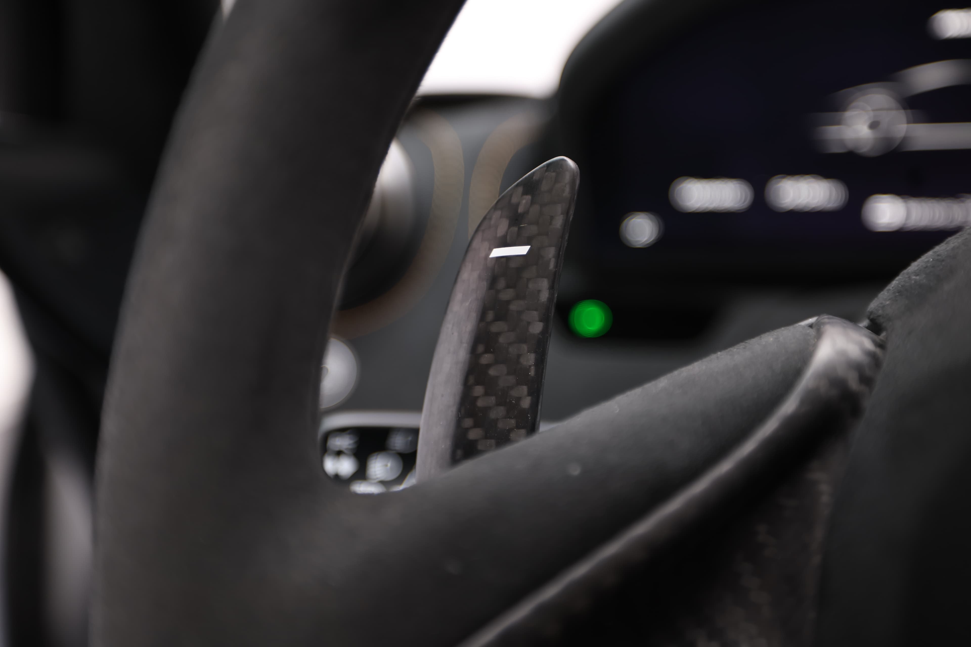 Gros plan sur les palettes de changement de vitesse en carbone du volant de la McLaren 765LT, illustrant la précision et la réactivité, conçues pour une expérience de conduite optimale.