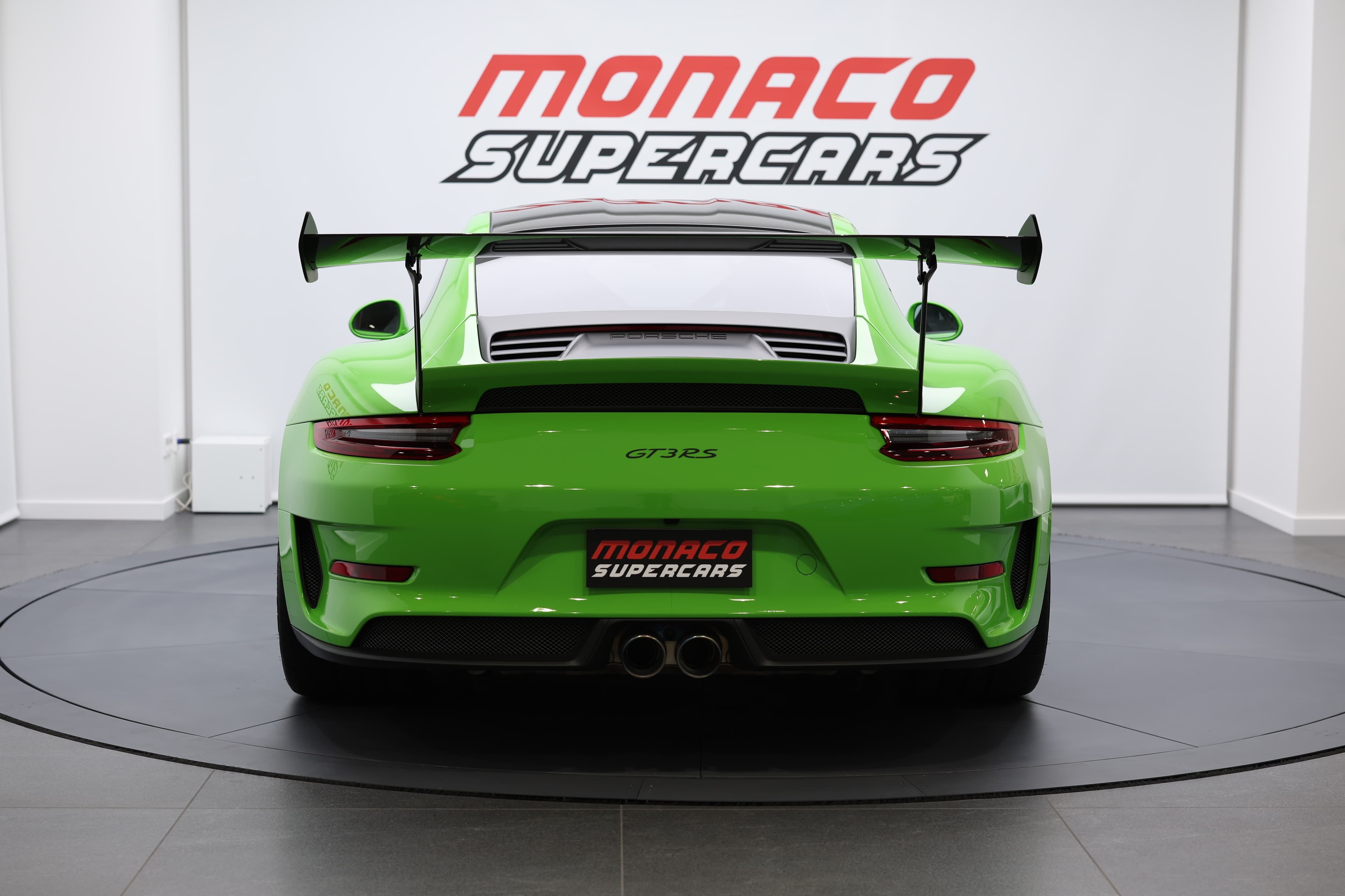 Supercar de prestige verte, vue arrière, équipée d’un large aileron arrière, d’un diffuseur sportif et de doubles sorties d’échappement centrales, idéale pour des expériences automobiles haut de gamme.