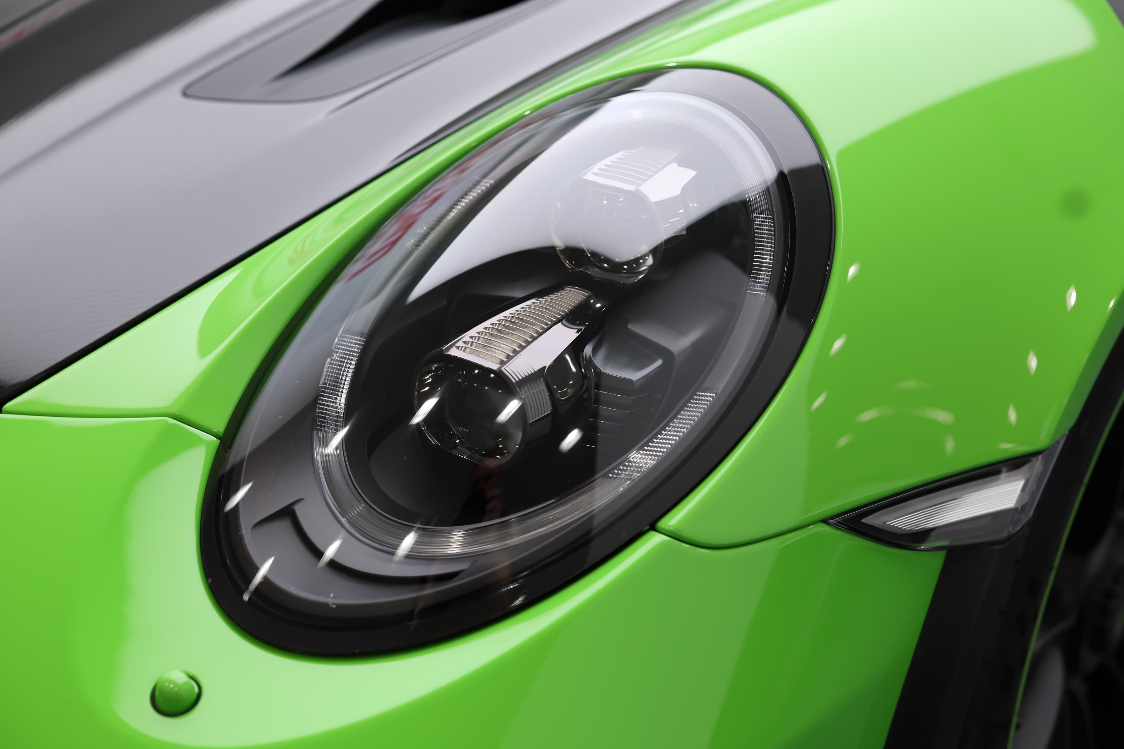 Détail du phare avant emblématique de la Porsche 911 GT3 RS 991 verte, soulignant son identité sportive et son design iconique immédiatement reconnaissable.