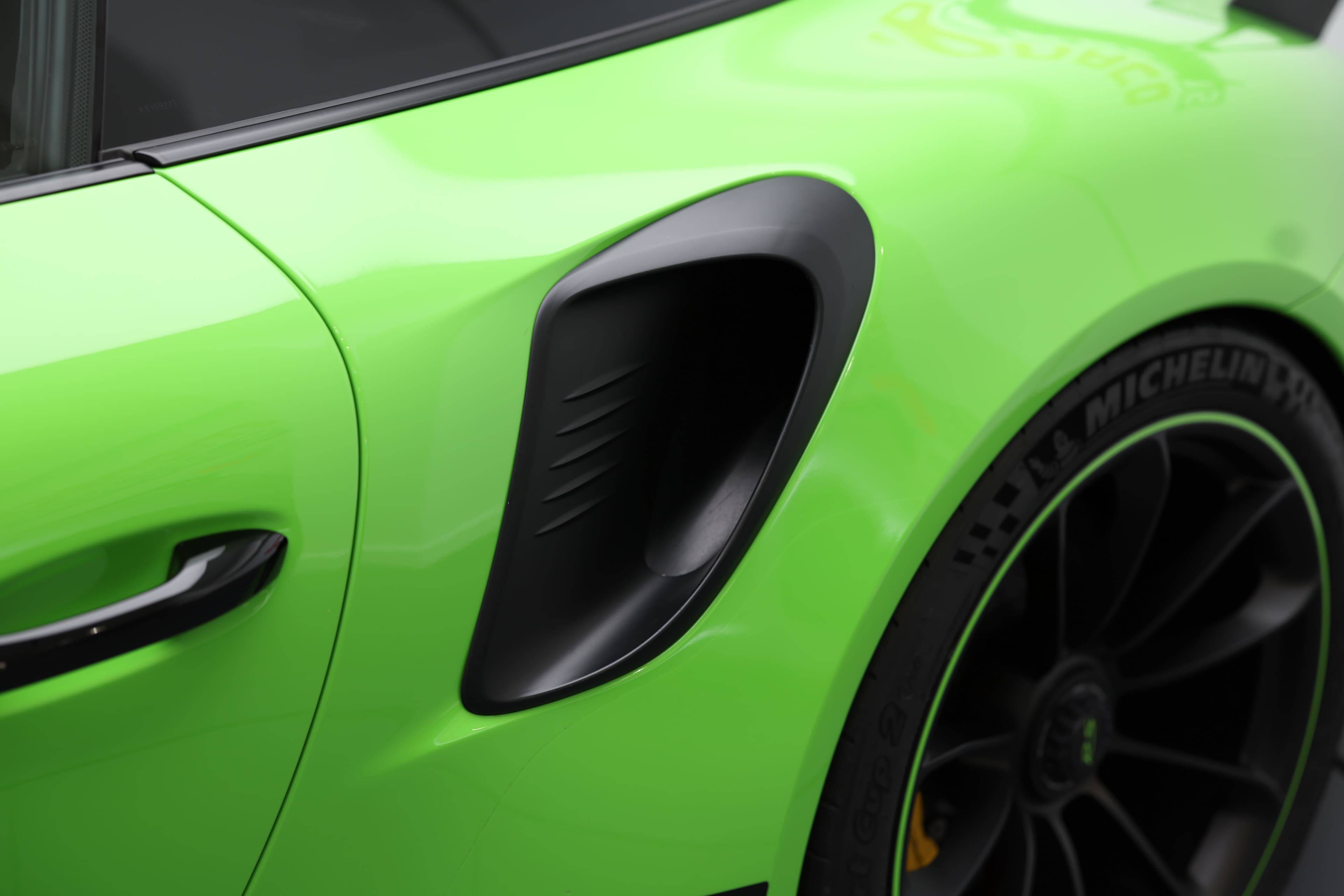 Détail de l’aile arrière de la Porsche 911 GT3 RS 991 verte mettant en valeur les prises d’air latérales spécifiques, conçues pour optimiser le refroidissement et les performances sur circuit.