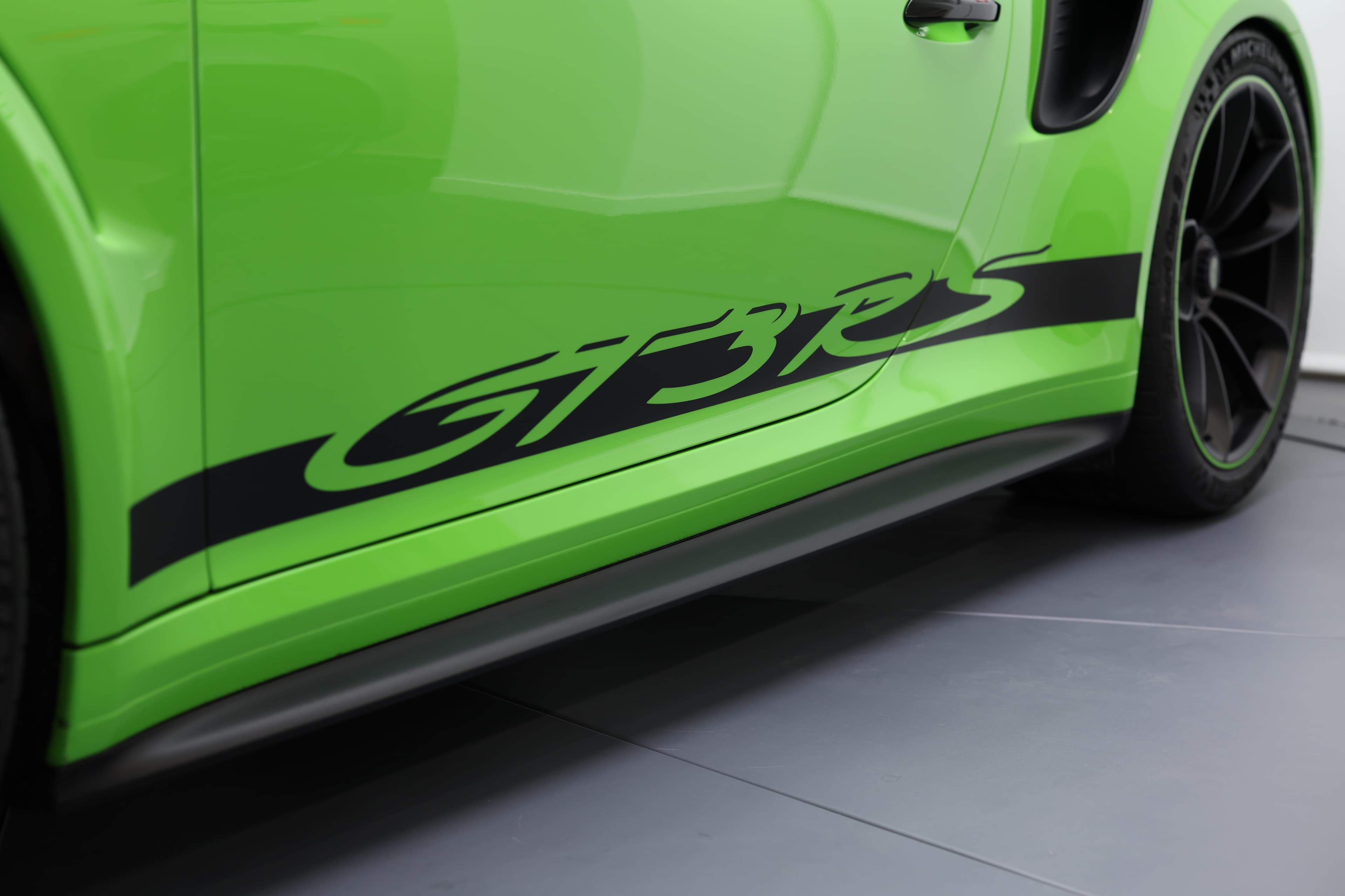 Détail du flanc de la Porsche 911 GT3 RS 991 verte avec marquage « GT3 RS » distinctif et bas de caisse sport, affirmant son caractère radical et orienté performance.