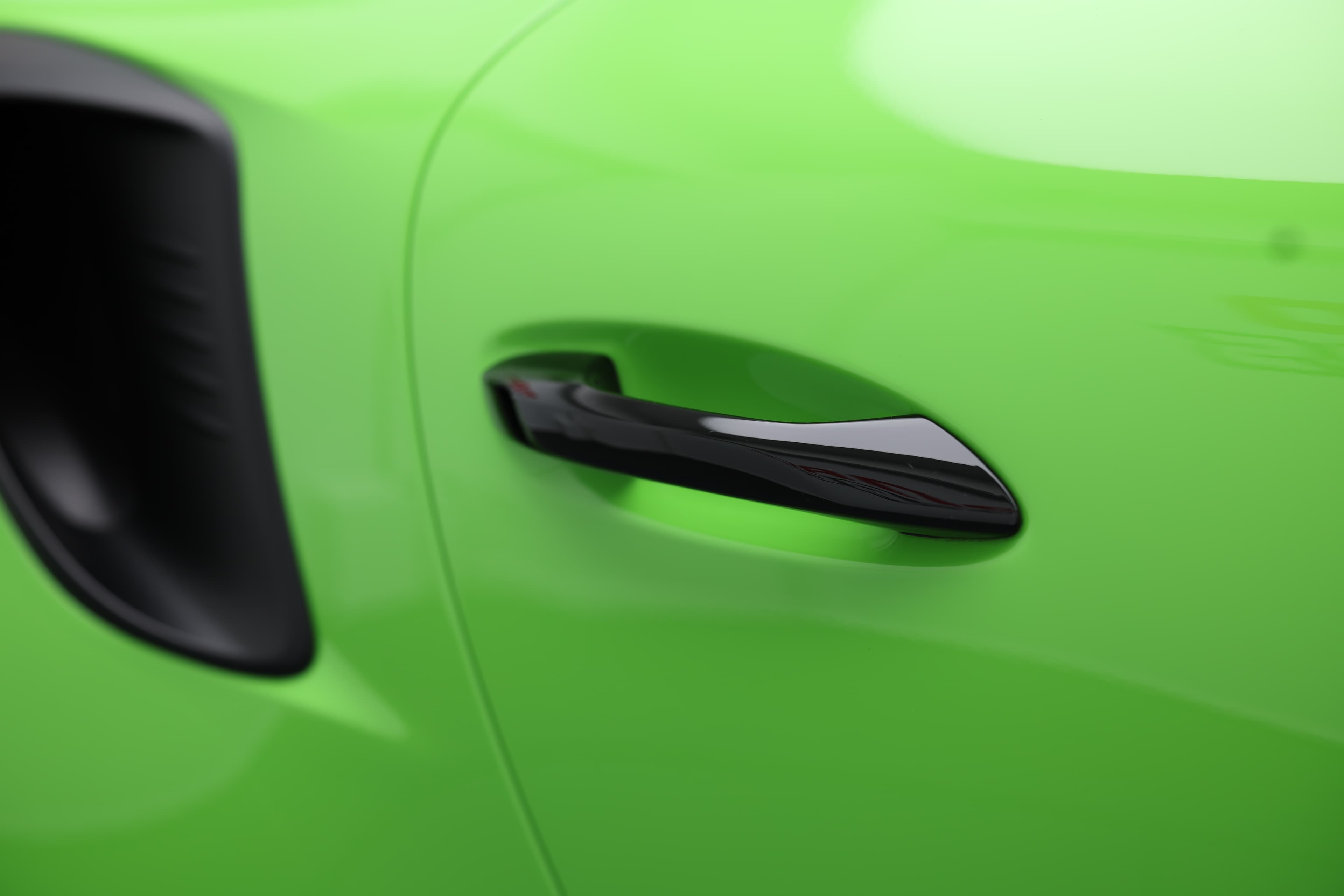 Détail de la porte de la Porsche 911 GT3 RS 991 verte mettant en valeur la poignée affleurante et la prise d’air latérale, soulignant son design fonctionnel et orienté performance.