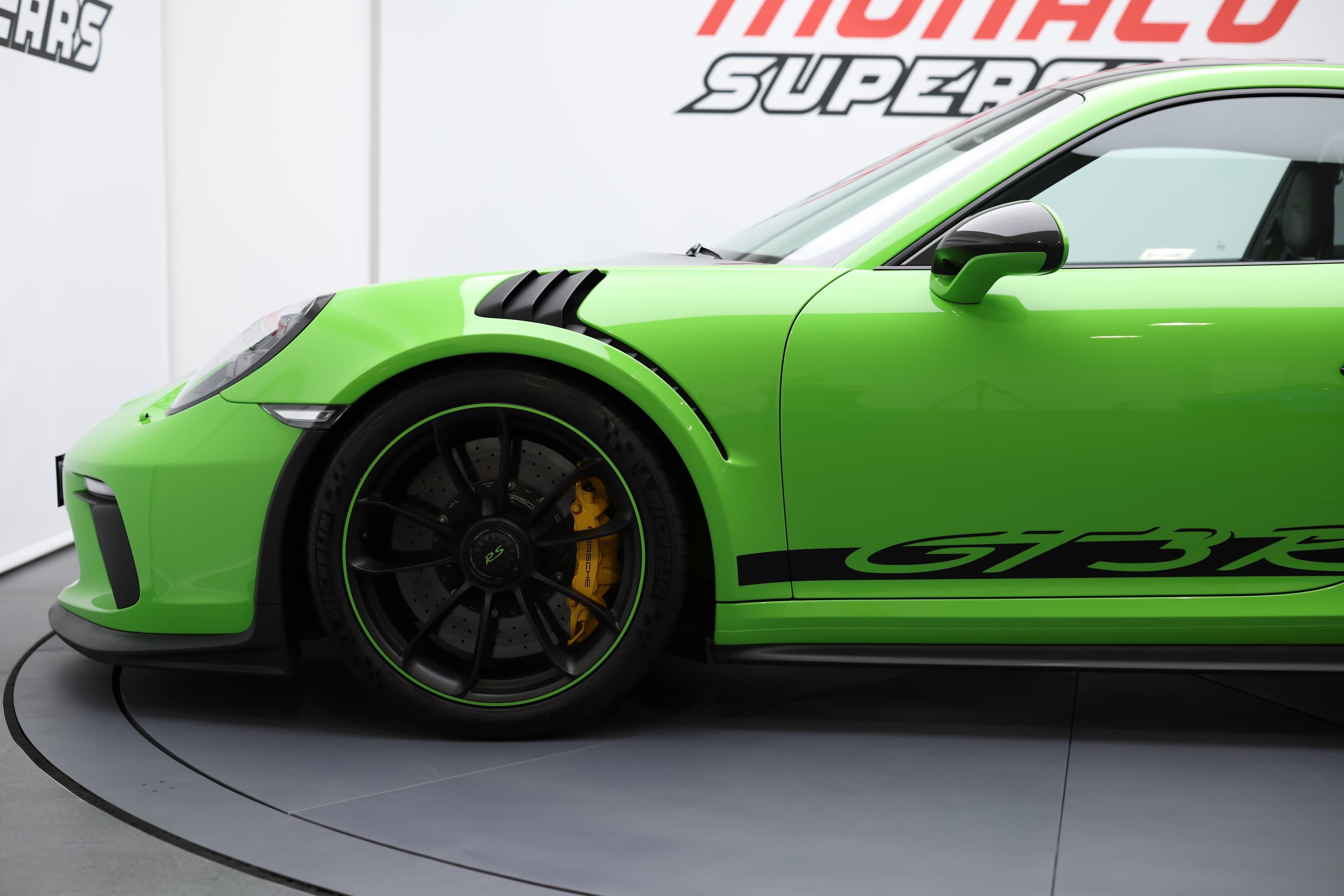 Vue latérale de la Porsche 911 GT3 RS 991 verte mettant en valeur ses jantes sport, ses prises d’air avant et son design radical inspiré de la compétition.