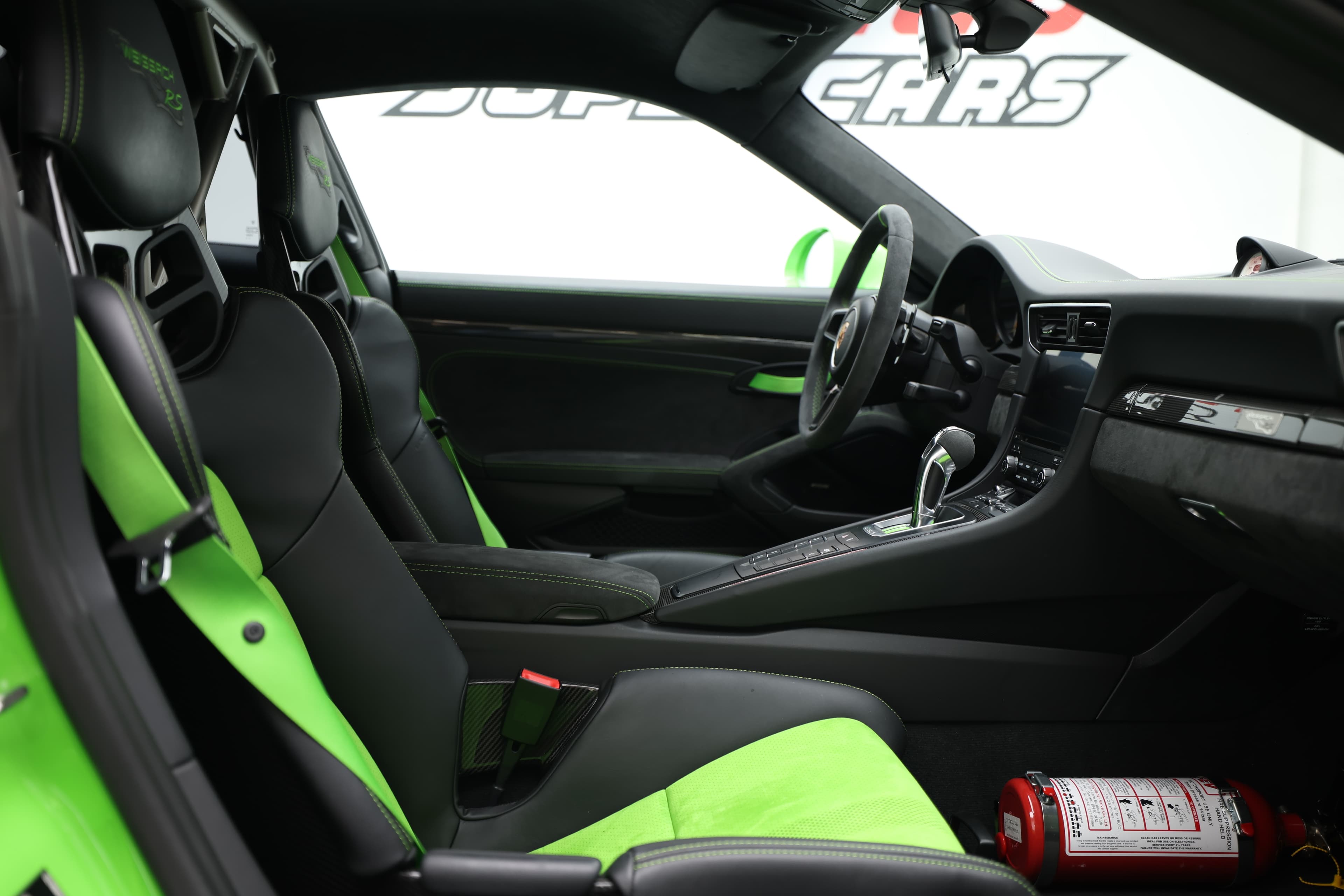 L'intérieur de la Porsche GT3 RS, avec ses sièges baquets en carbone et ses accents verts, allie confort et sportivité, créant une ambiance de course qui ravira les passionnés de performance.