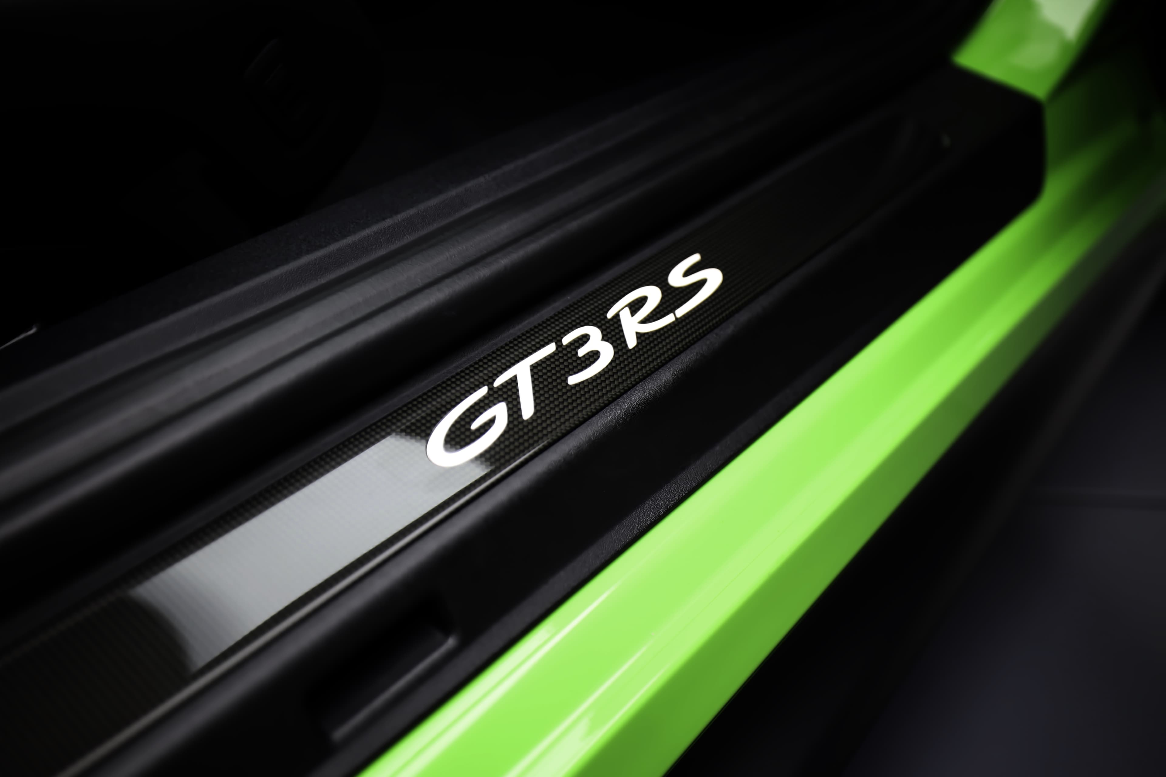 Le seuil de porte carbone de la Porsche GT3 RS, affichant le logo emblématique, incarne l'âme sportive de la voiture, tout en ajoutant une touche de sophistication à ce modèle d’exception.