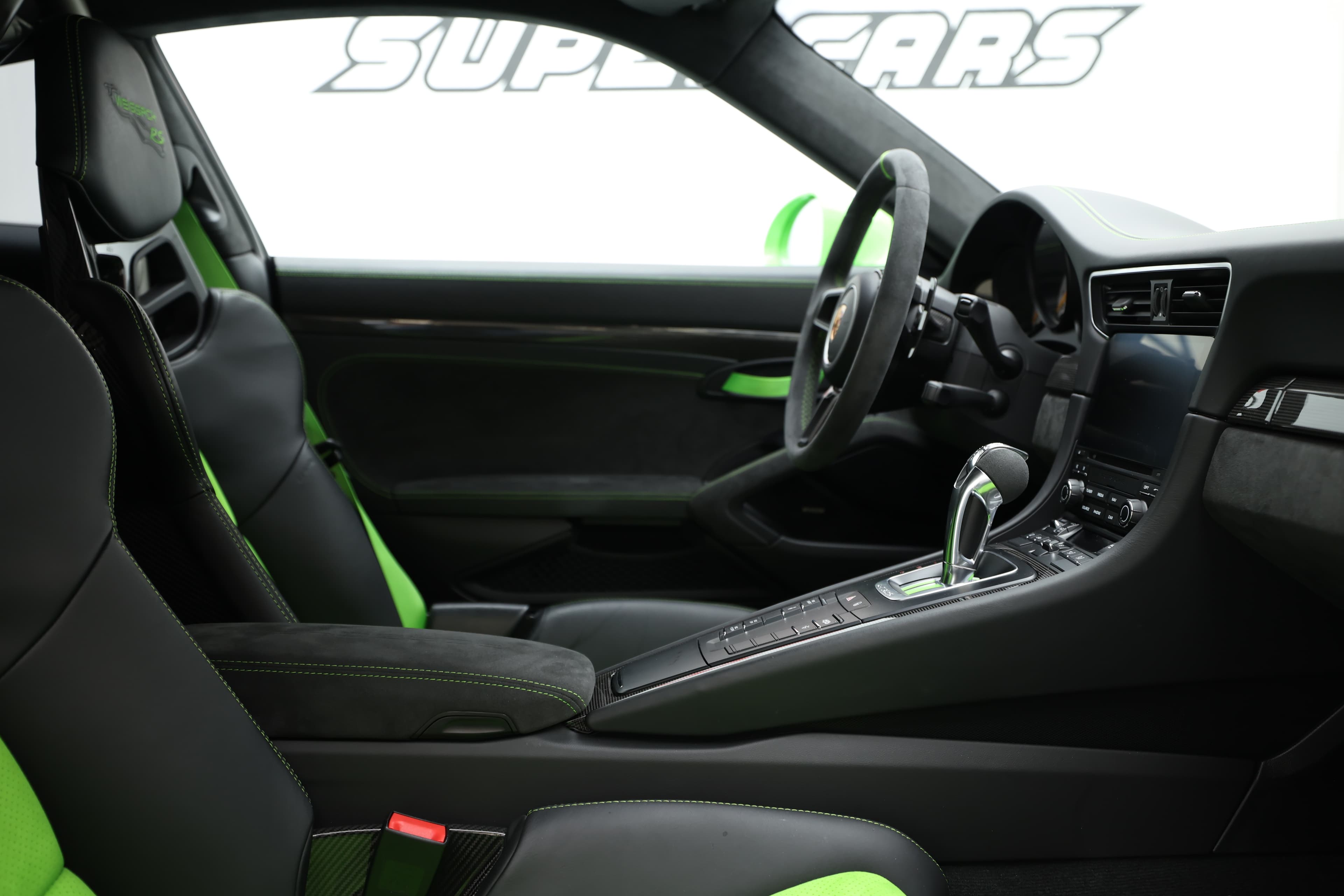 L'intérieur de la Porsche GT3 RS, avec ses sièges sport et son volant ergonomique, met en avant un design fonctionnel et une esthétique audacieuse, accentuée par des détails verts qui soulignent son caractère dynamique.