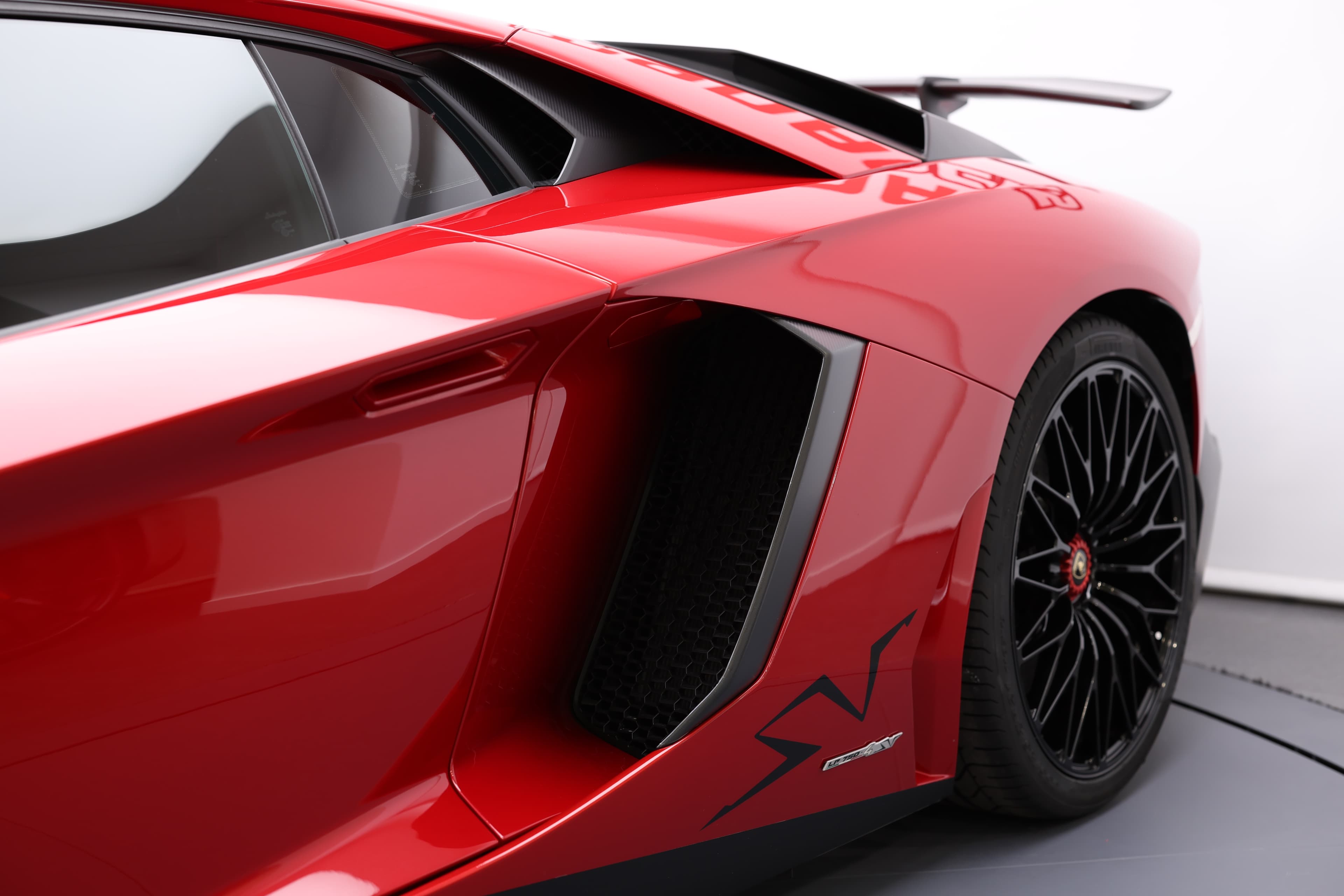 Examinez le profil dynamique de la Lamborghini Aventador SV, mettant en valeur ses prises d'air sculptées et son aileron arrière, conçus pour optimiser l'aérodynamisme et la performance sur route.