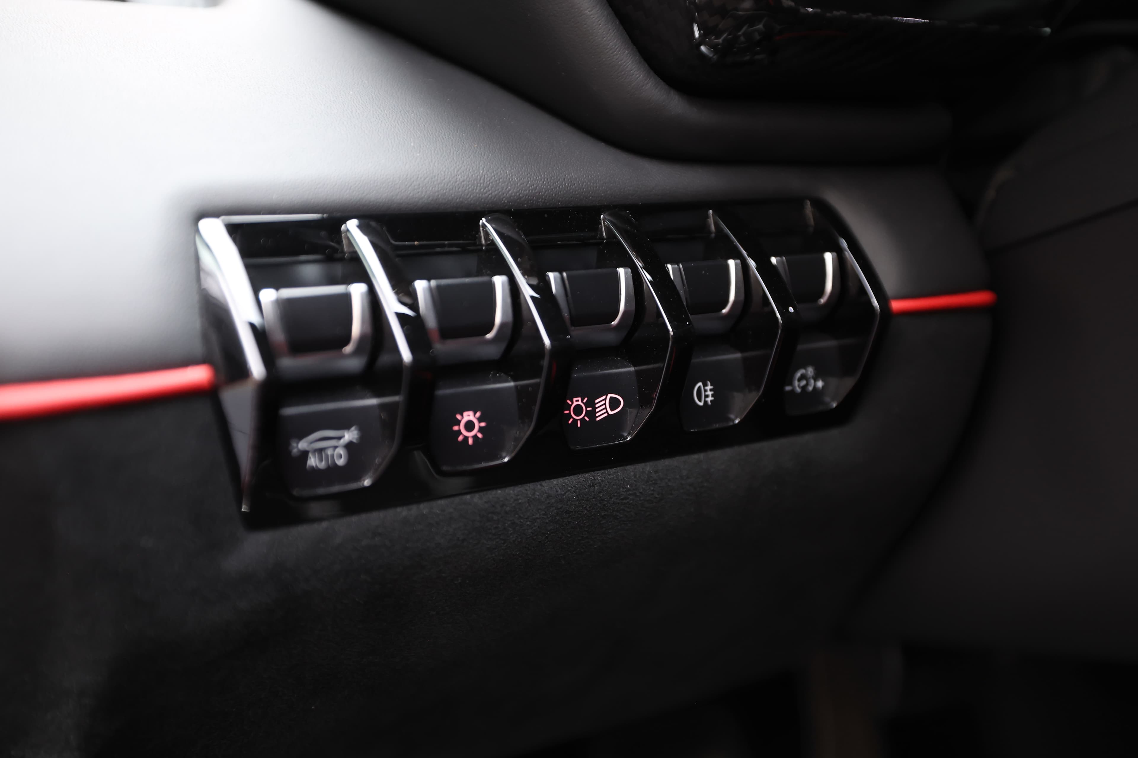 Vue des commandes situées sur le panneau de porte de la Lamborghini Aventador SV. Les boutons en finition brillante, accompagnés d'accents rouges, permettent de contrôler diverses fonctions, comme l'éclairage et les réglages du véhicule. Ce design allie ergonomie et esthétique, renforçant l'expérience de conduite de luxe tout en conservant un look sportif.