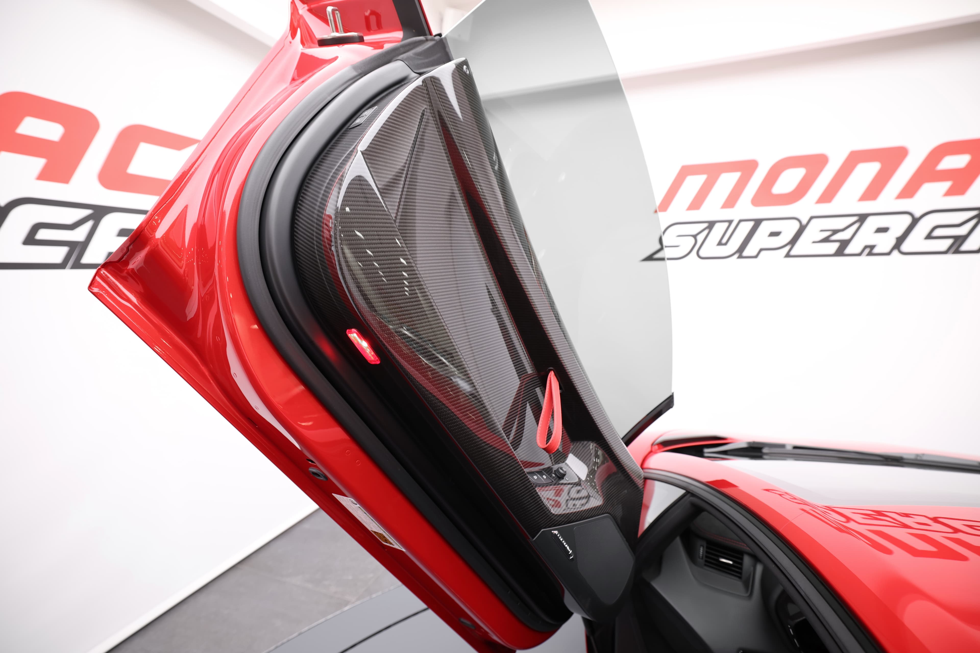 Détail de l'ouverture de la porte de la Lamborghini Aventador SV. Le design en porte-à-faux, caractéristique de Lamborghini, permet un accès facile à l'intérieur tout en offrant une esthétique saisissante. La finition rouge et les courbes élégantes de la porte ajoutent à l'allure sportive et dynamique de ce supercar, frappant à la fois par sa performance et son style.