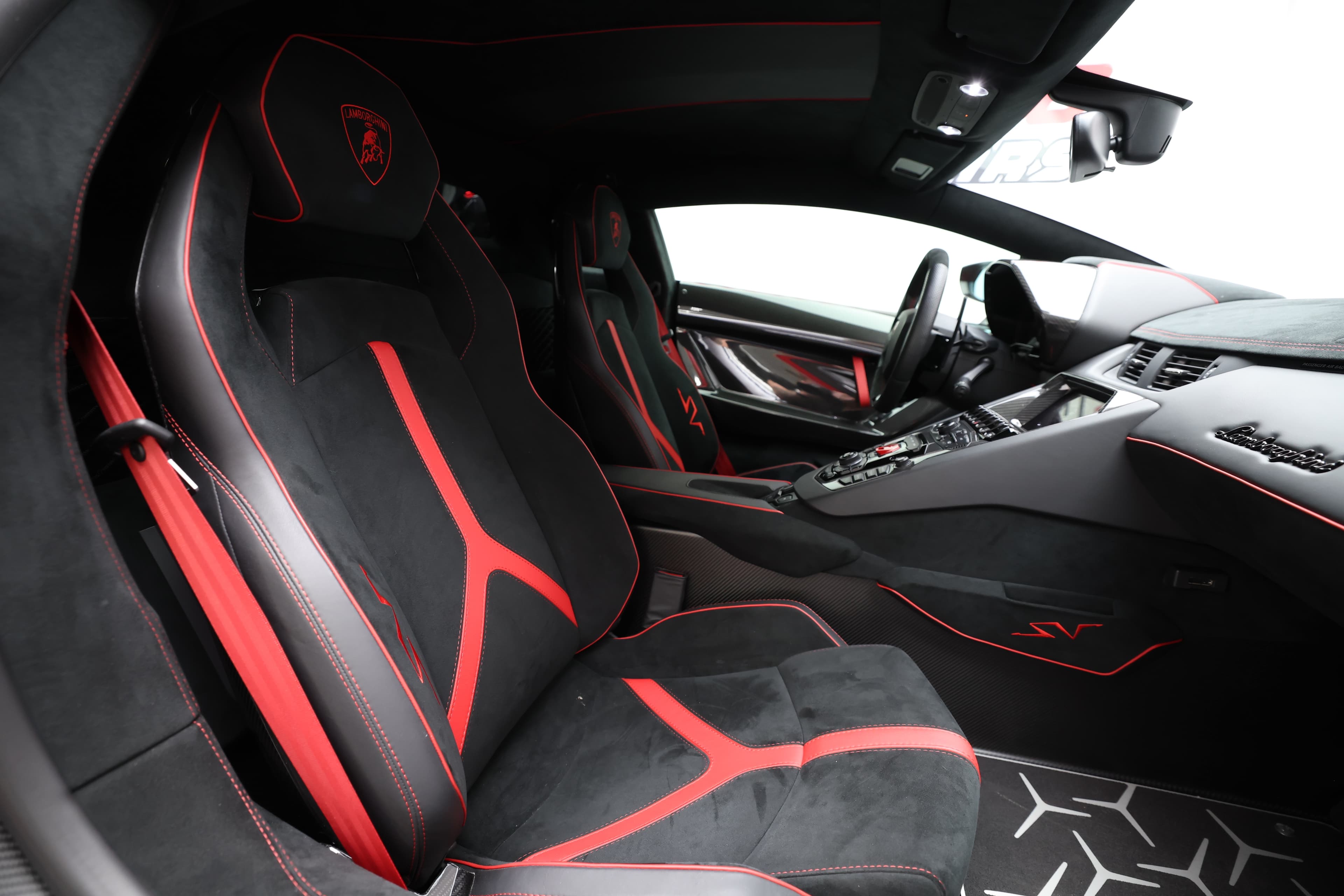 Sièges sport en alcantara avec accents rouges dans l'intérieur luxueux de la Lamborghini, alliant confort et performance.