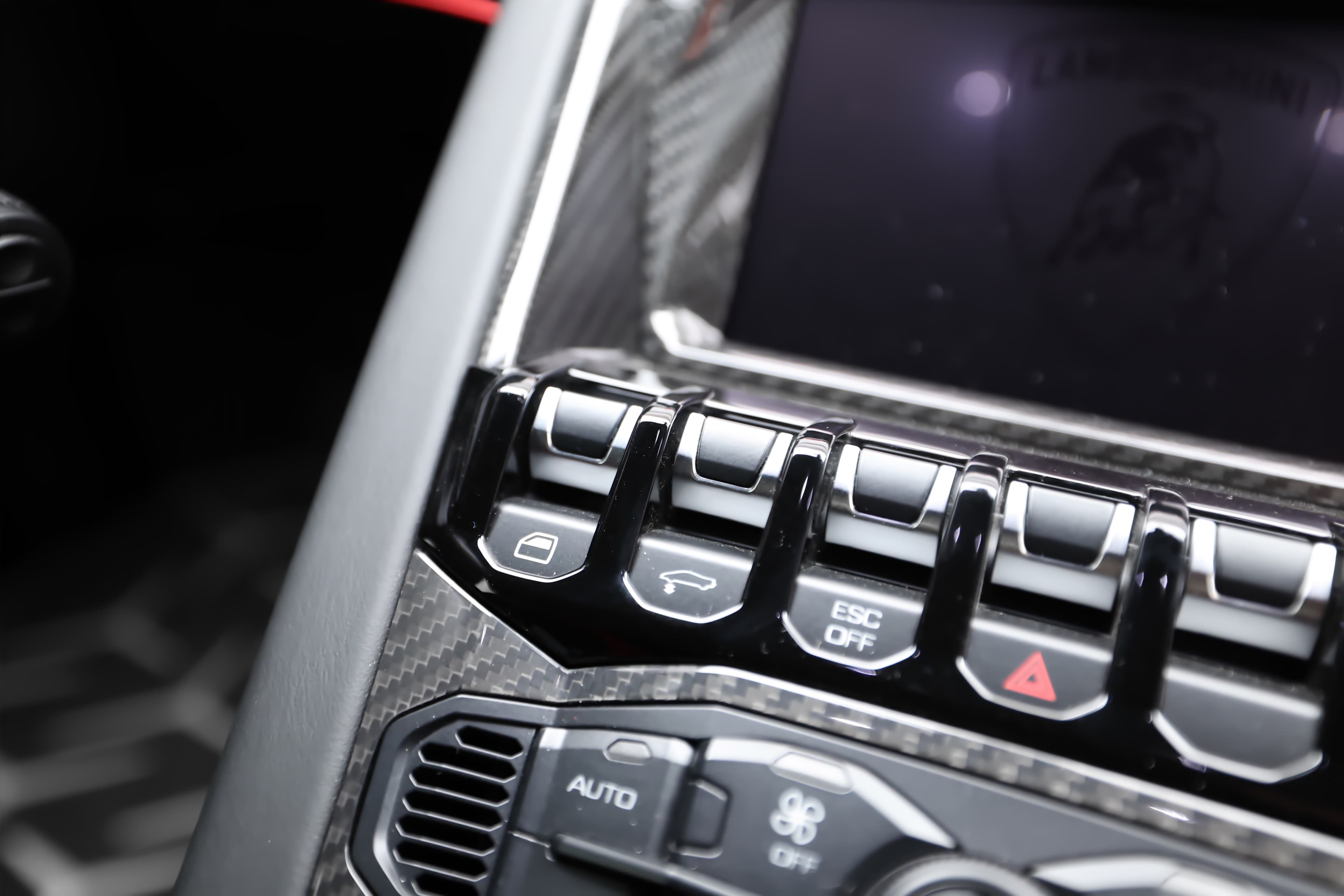 Détails des commandes en carbone dans l'intérieur de la Lamborghini, alliant ergonomie et esthétique sportive.