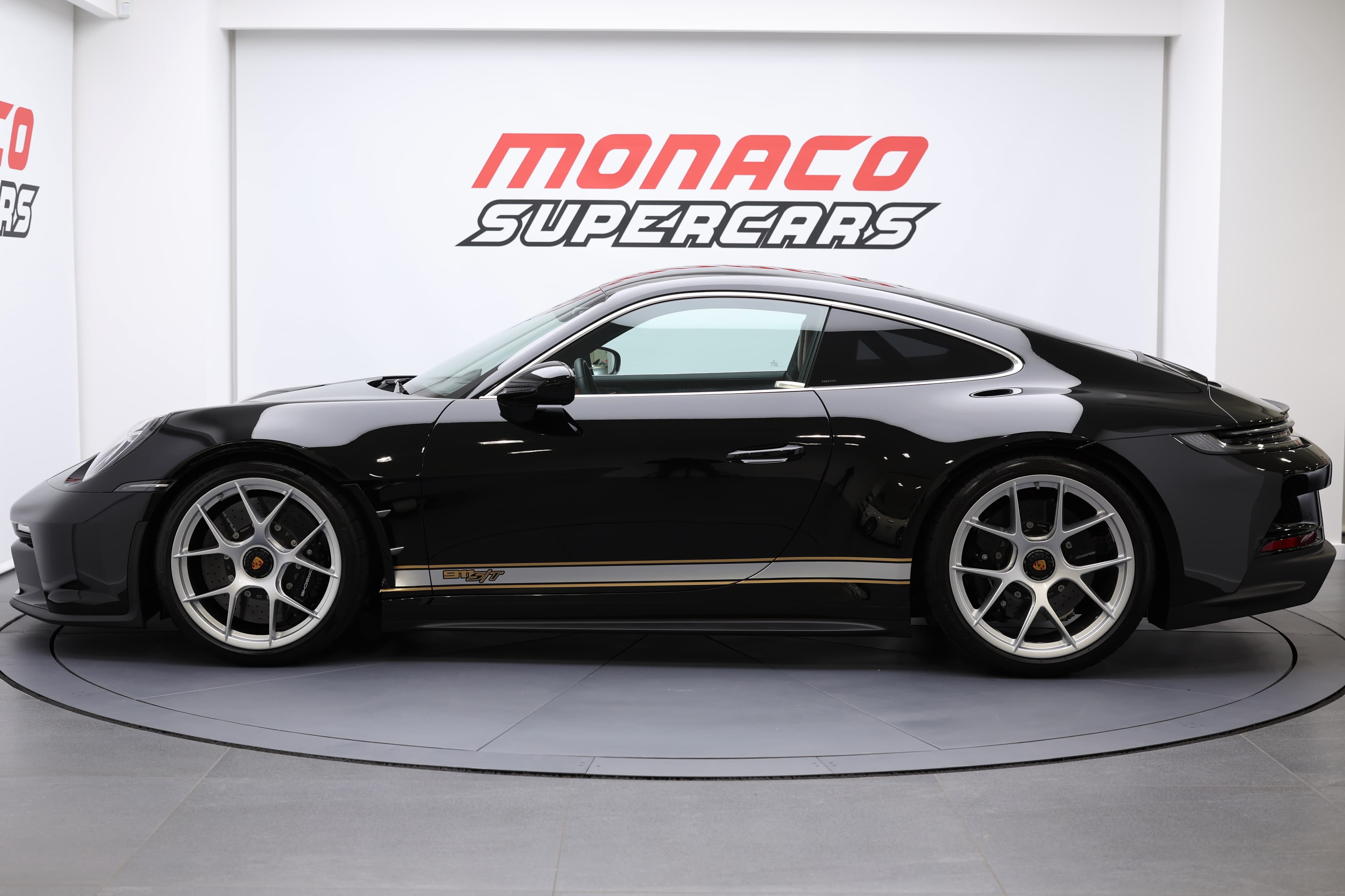 Porsche 911 en noir, vue de profil, présentée à Monaco Supercars, alliant design sportif et luxe, captivant les passionnés d'automobiles.