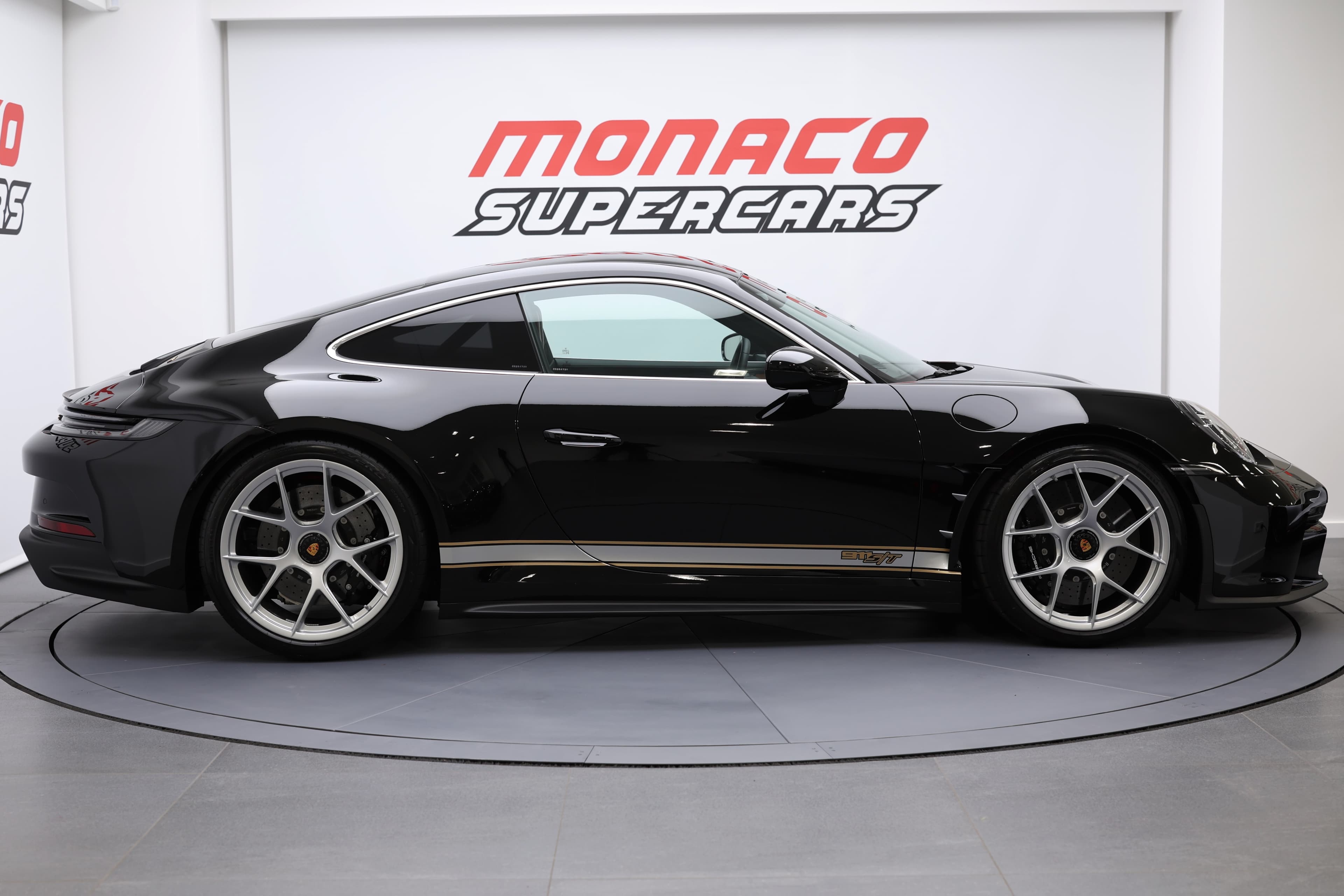 Porsche 911 en noir, vue latérale, mettant en valeur son design élégant et ses jantes sportives, présentée à Monaco Supercars, alliant style et performance.