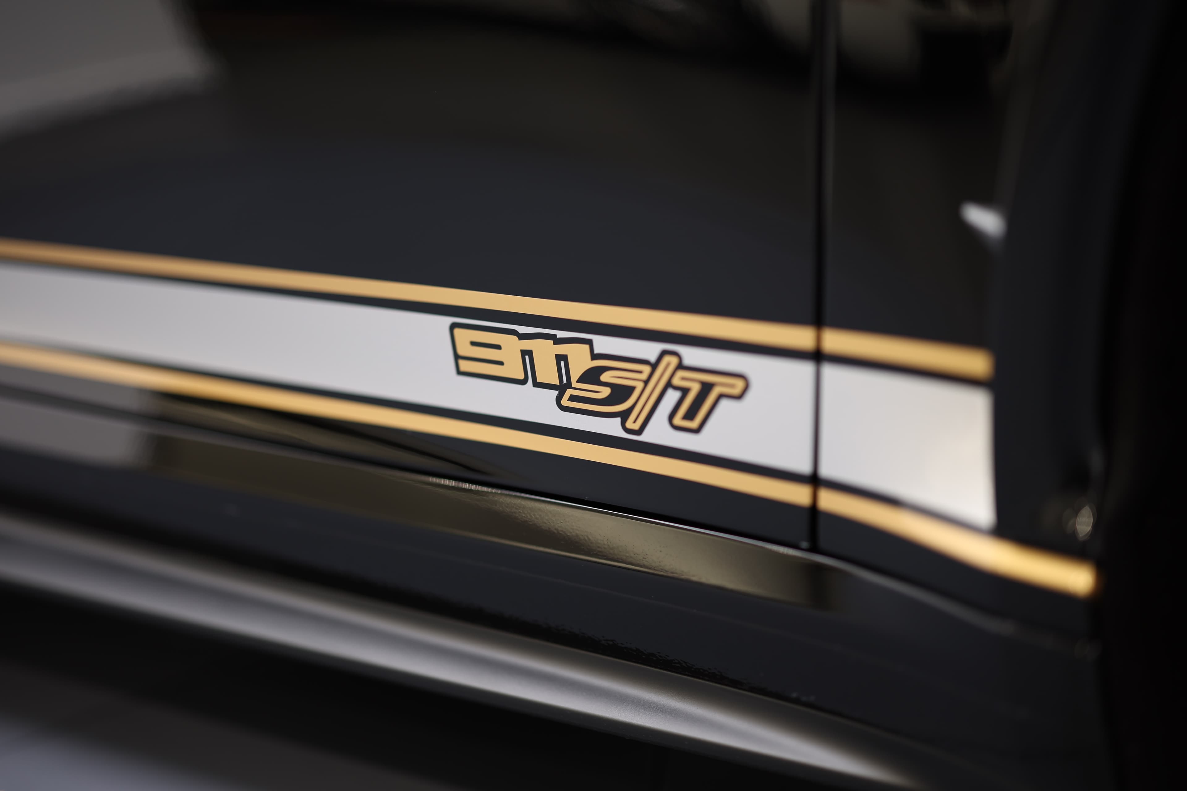 Détail du logo "911 S/T" sur la Porsche, mettant en avant l'identité unique et les performances spéciales de ce modèle, un clin d'œil à l'héritage sportif de la marque.