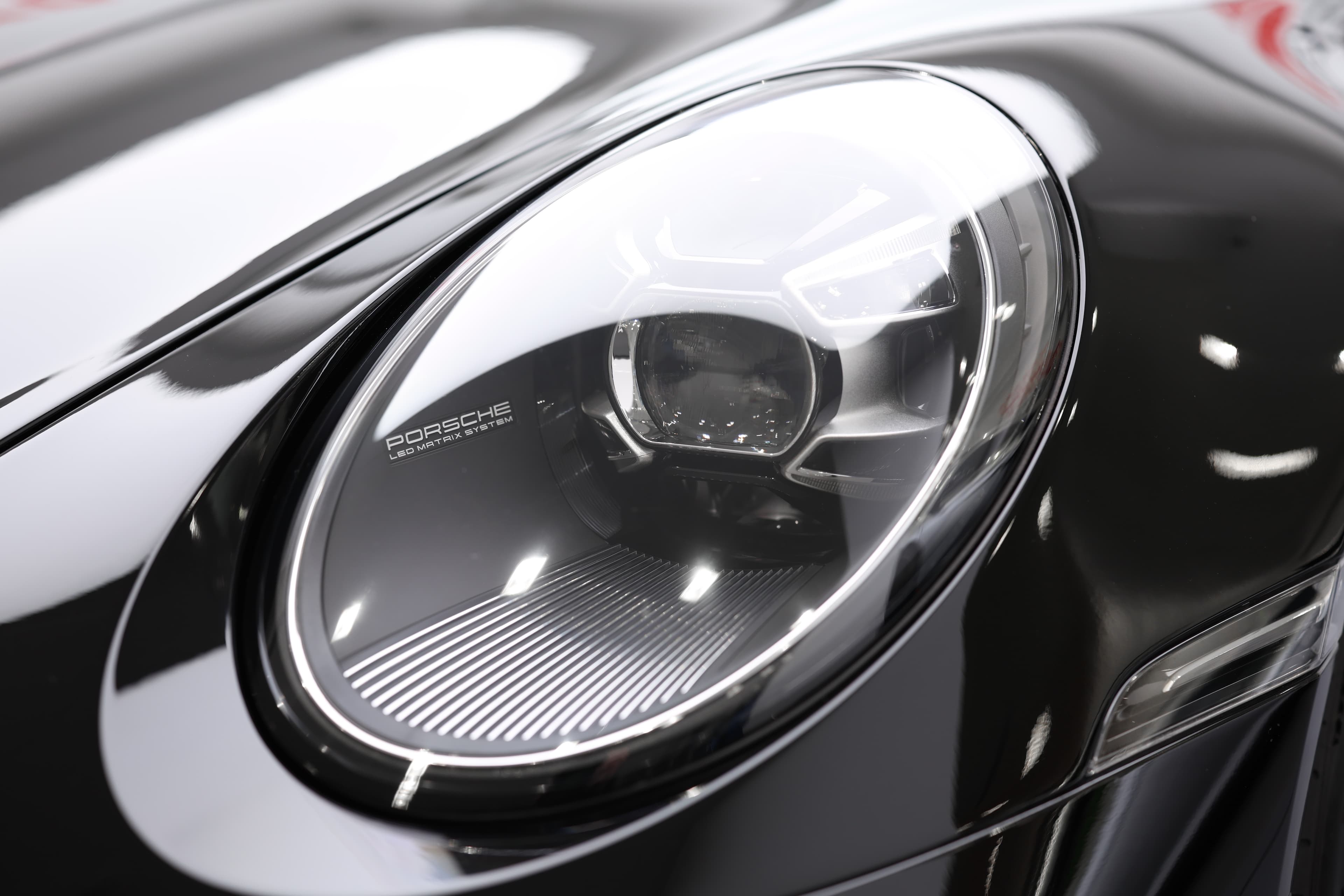 Détail du phare de la Porsche 911, mettant en avant son design distinctif et moderne, combinant esthétique et technologie avancée, symbole de sécurité et de performance sur la route.