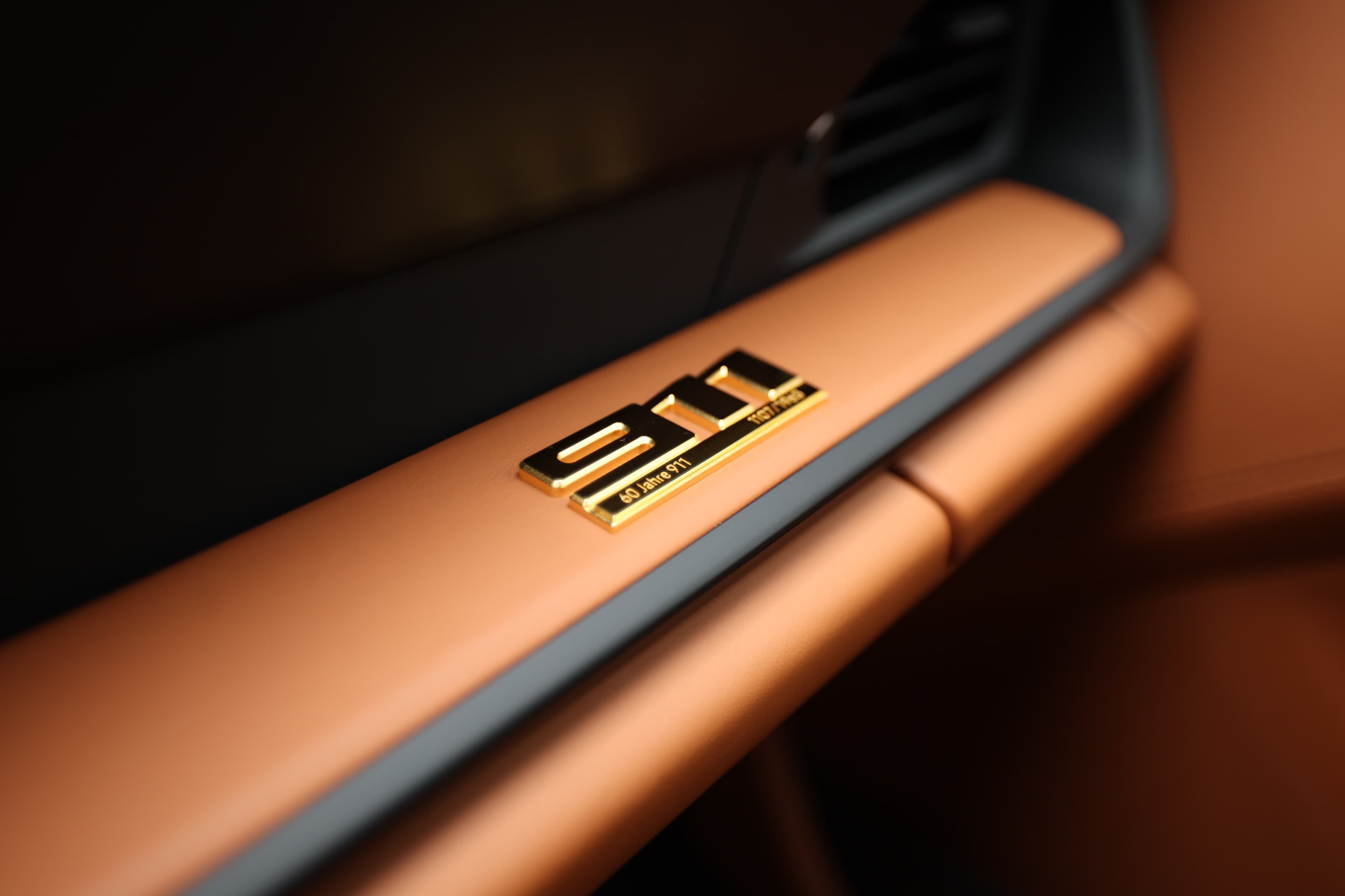 Détail du badge "911" sur le tableau de bord. Ce logo emblématique est en métal brillant, ajoutant une touche de sophistication à l'intérieur. Il souligne l'héritage et l'authenticité de cette voiture légendaire.